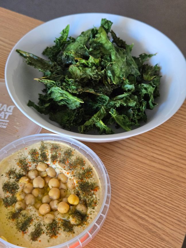 A bowl of airfried kale chips and hummus.